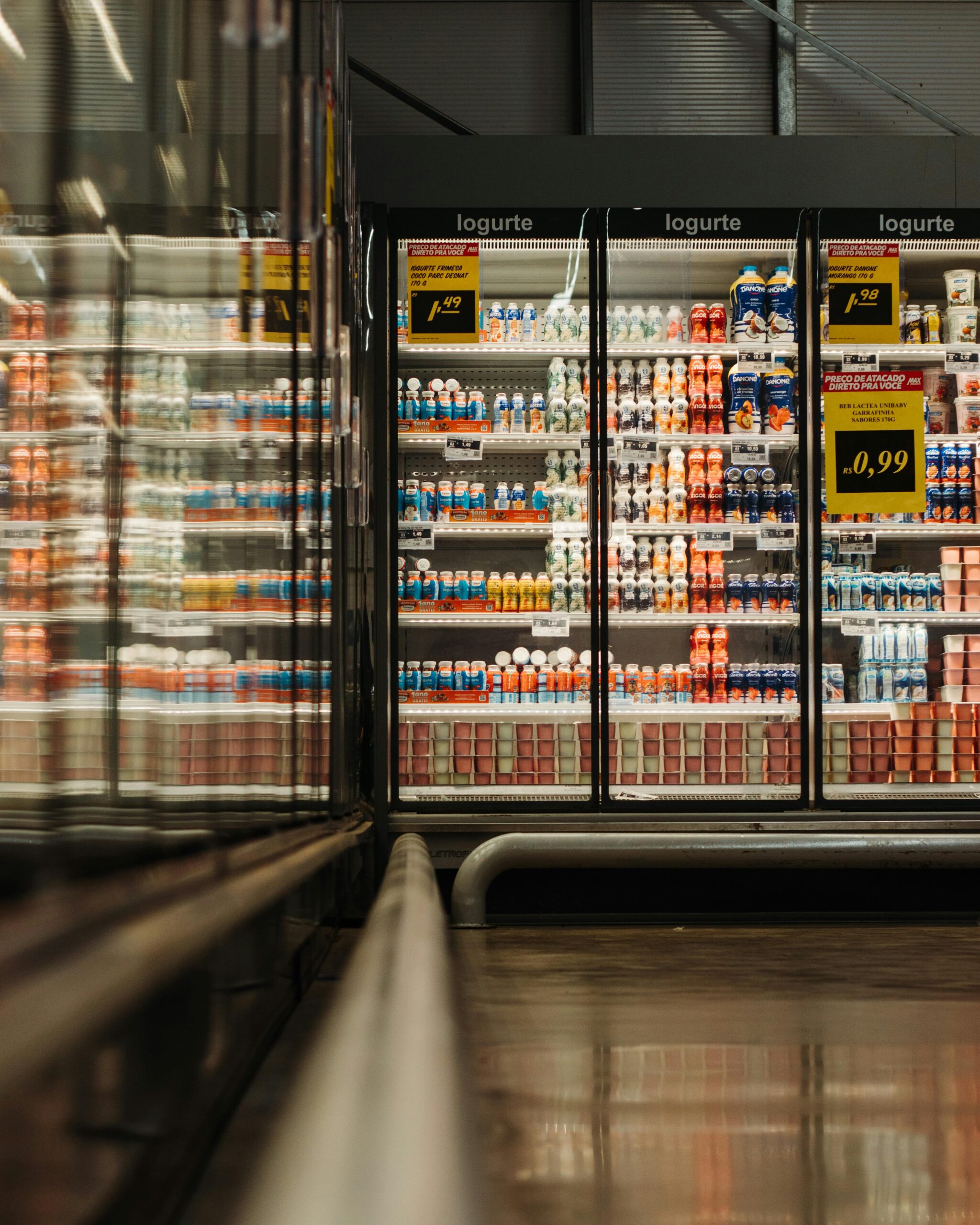A well-lit supermarket aisle showcasing a variety of yogurt products in a refrigerated display.